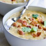 Roasted Poblano Corn Chowder in white bowl garnished with cilantro sprigs.