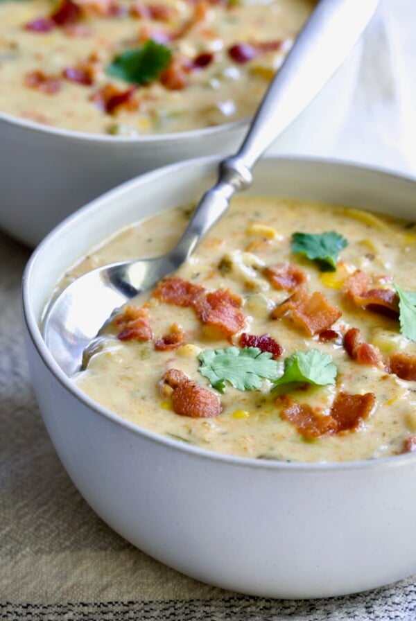 Roasted Poblano Corn Chowder in white bowl garnished with cilantro sprigs.