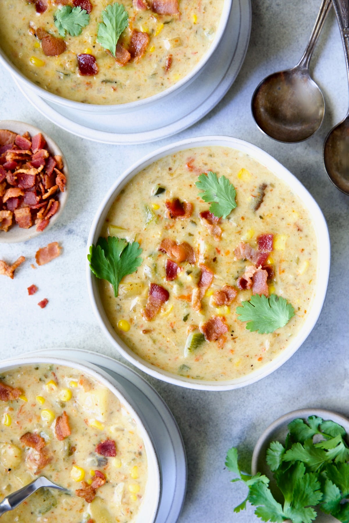 Three bowls of Roasted Poblano Corn Chowder garnished with cilantro.