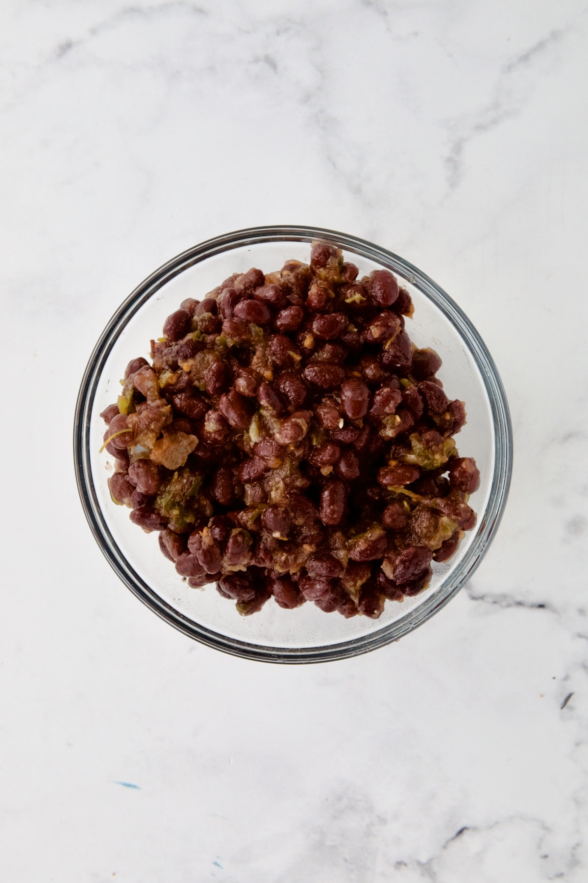 Black beans combined with salsa in glass bowl.