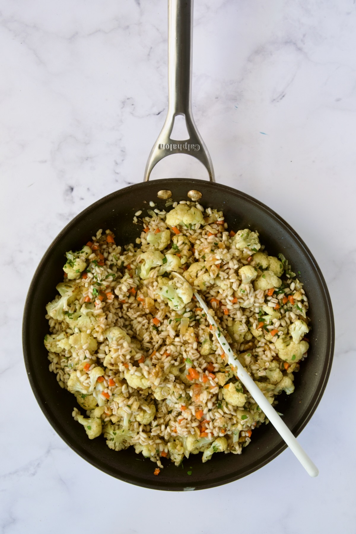 Barley pilaf being stirred together in nonstick skillet.