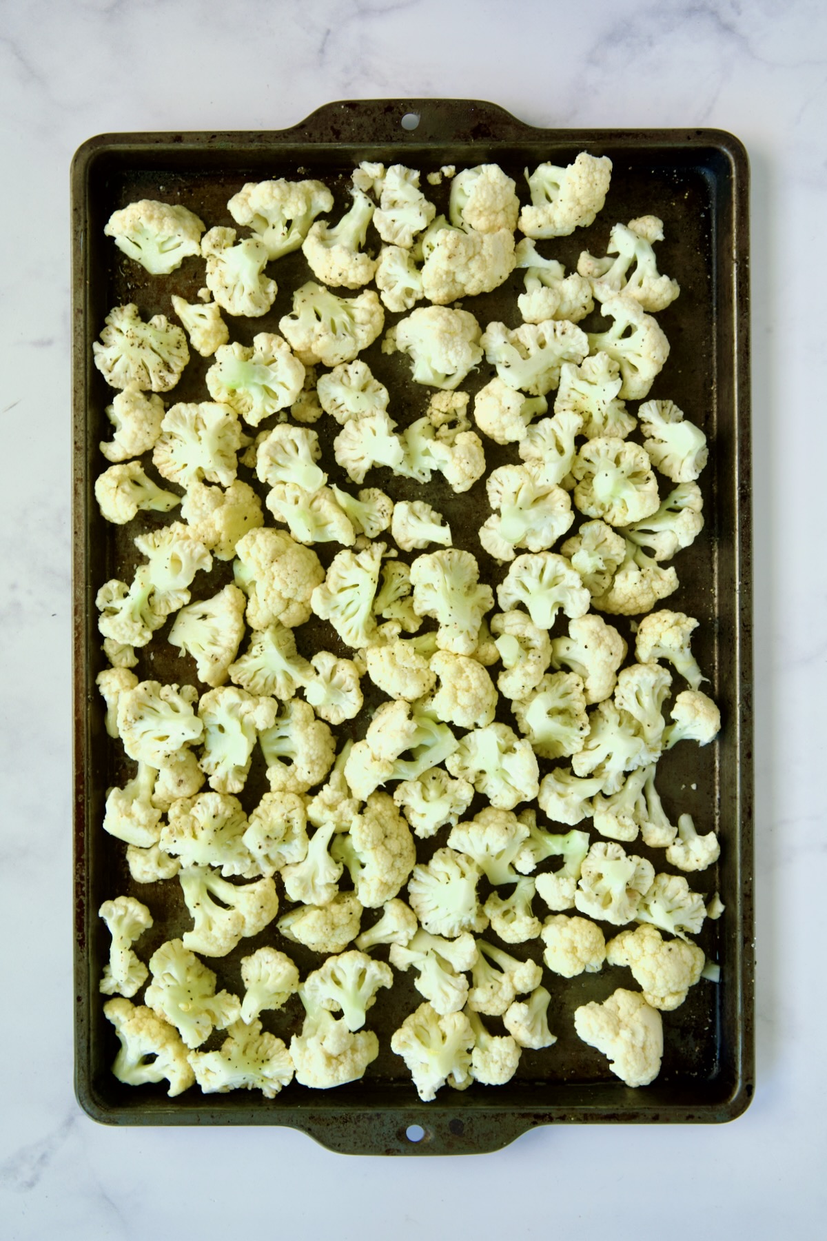Raw cauliflower on rimmed sheet pan.