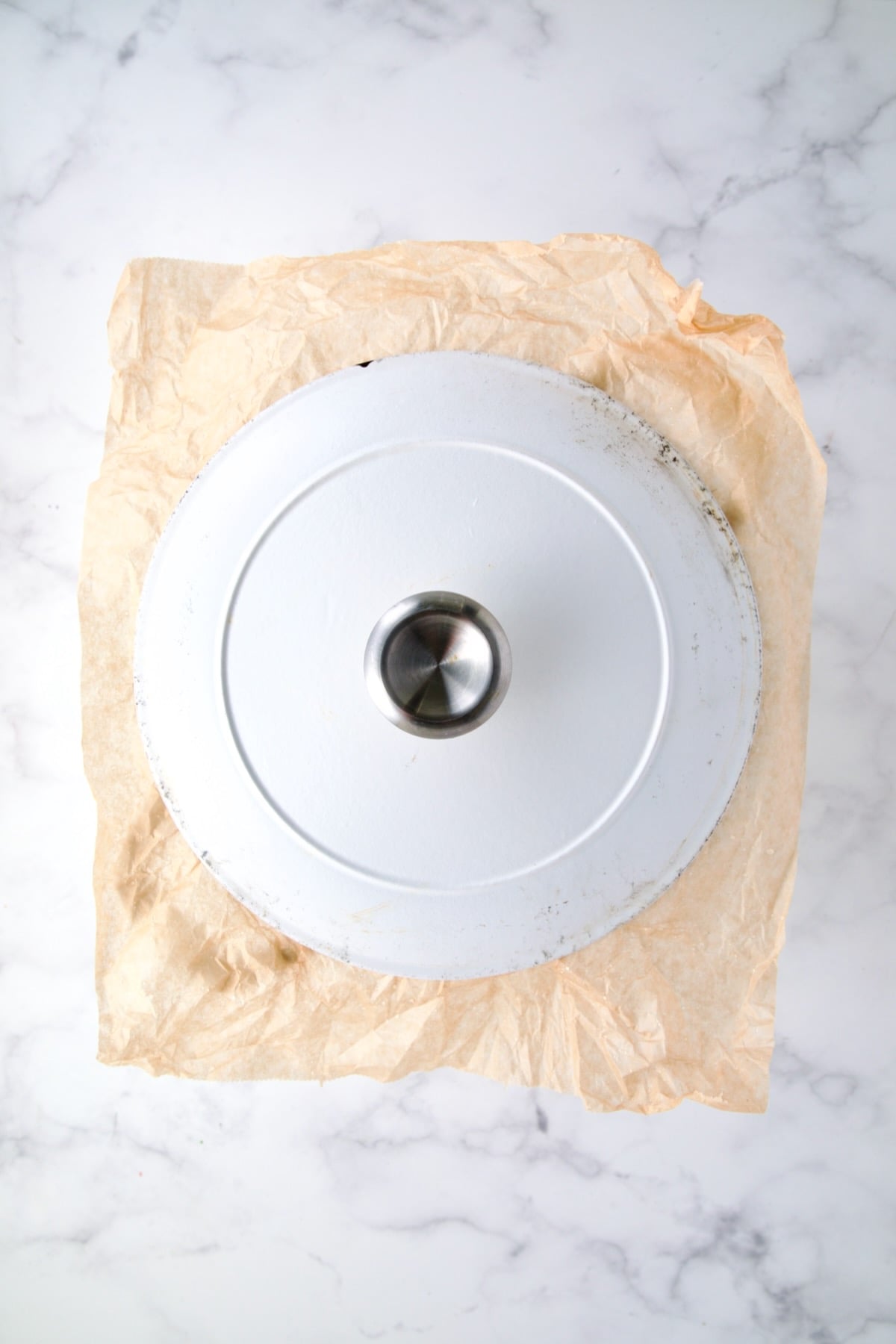 Top down photo showing parchment paper under the cover for a Dutch oven demonstrating how to seal it.