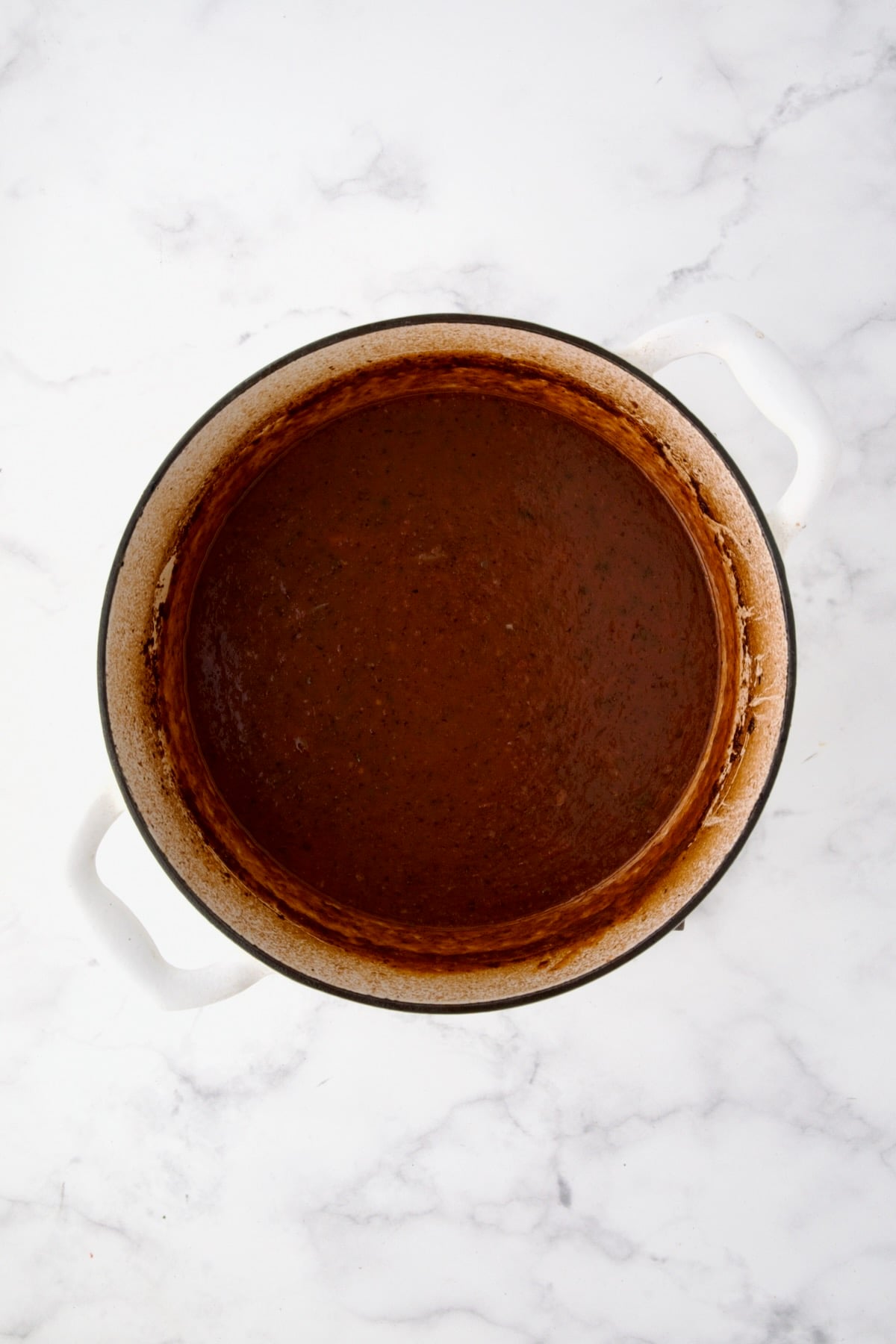 Thickened sauce in white Dutch oven.