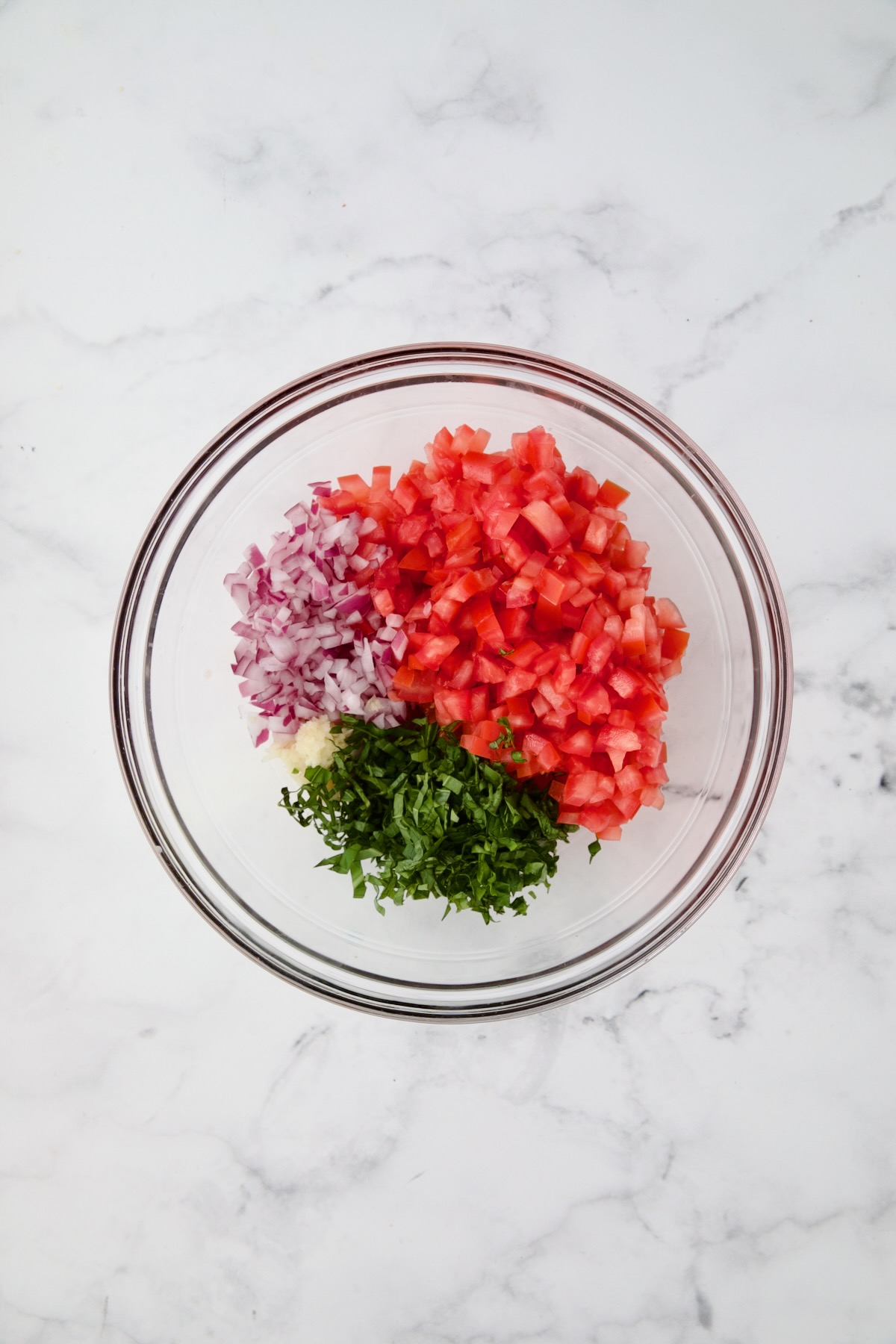 Tomato topping for chicken in glass bowl before being combined.