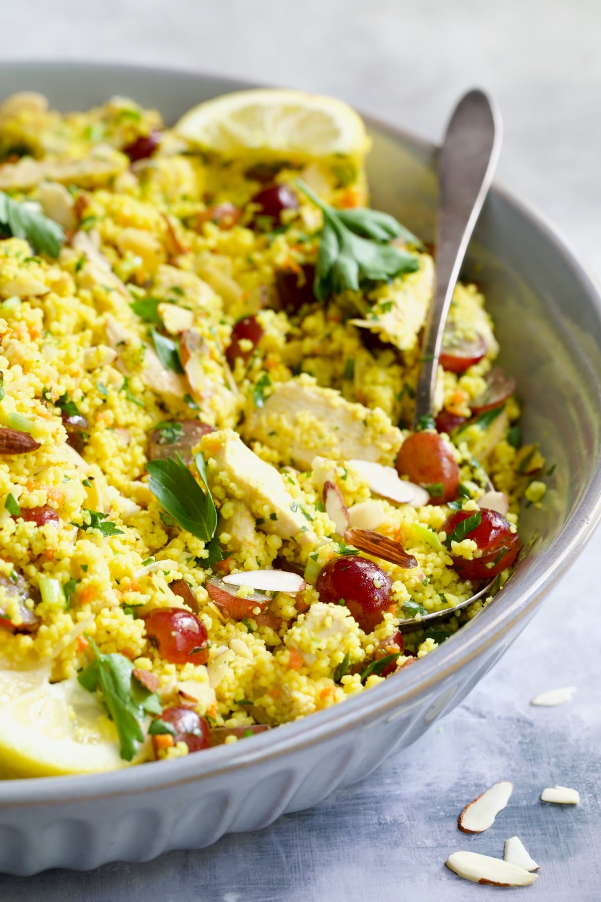 Chicken Couscous Salad in gray bowl with serving spoon.