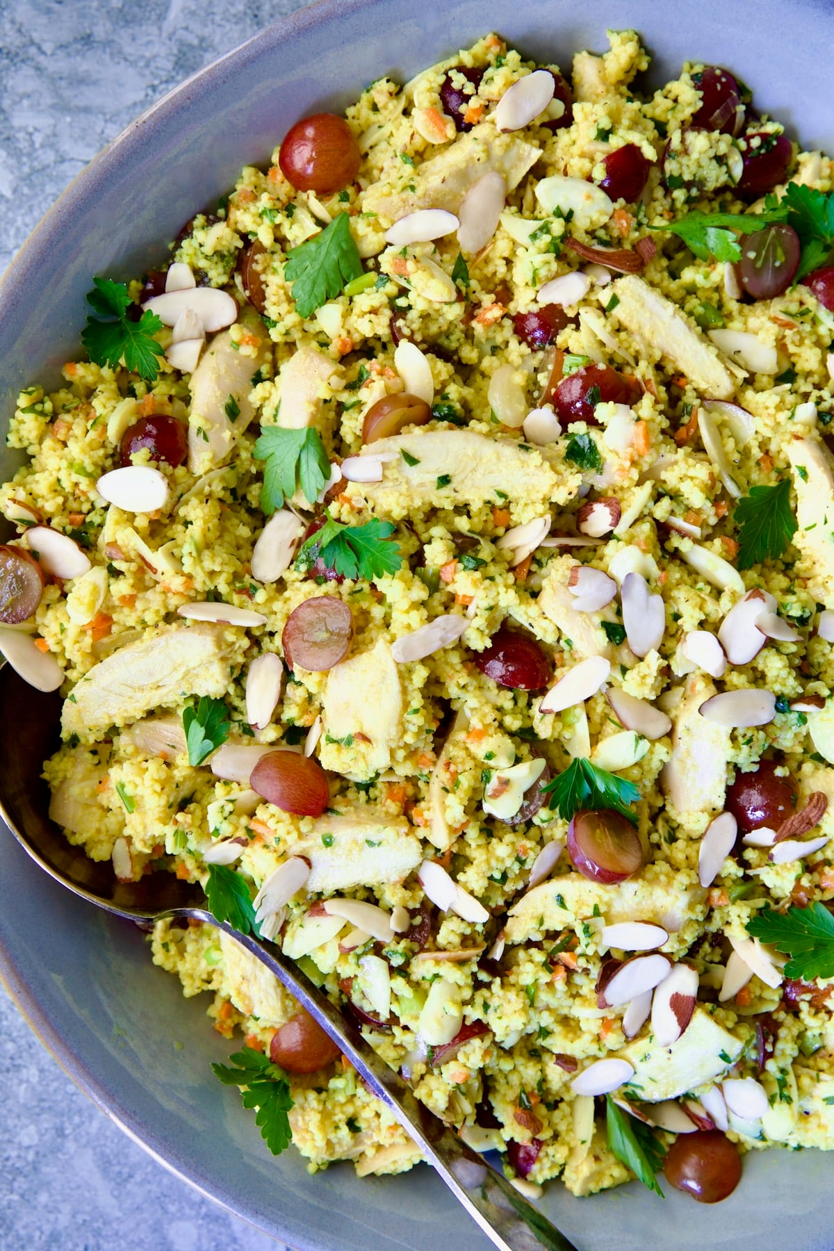 Chicken Couscous Salad in gray bowl with serving spoon.