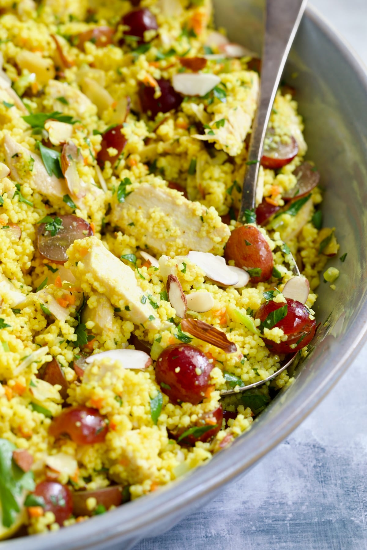 Chicken Couscous Salad in gray bowl with serving spoon.