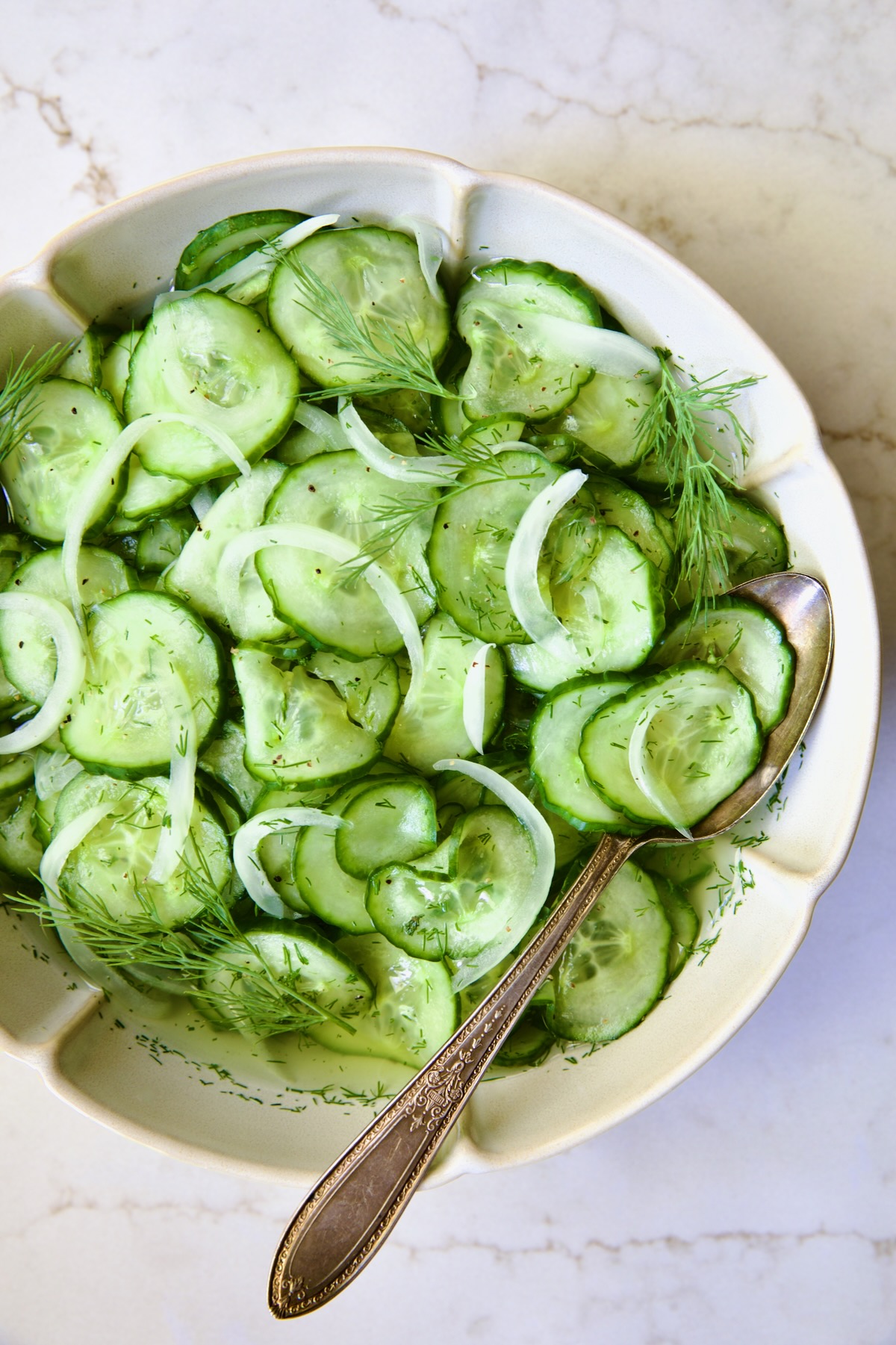 Cucumber Onion Salad in serving bowl with serving spoon.
