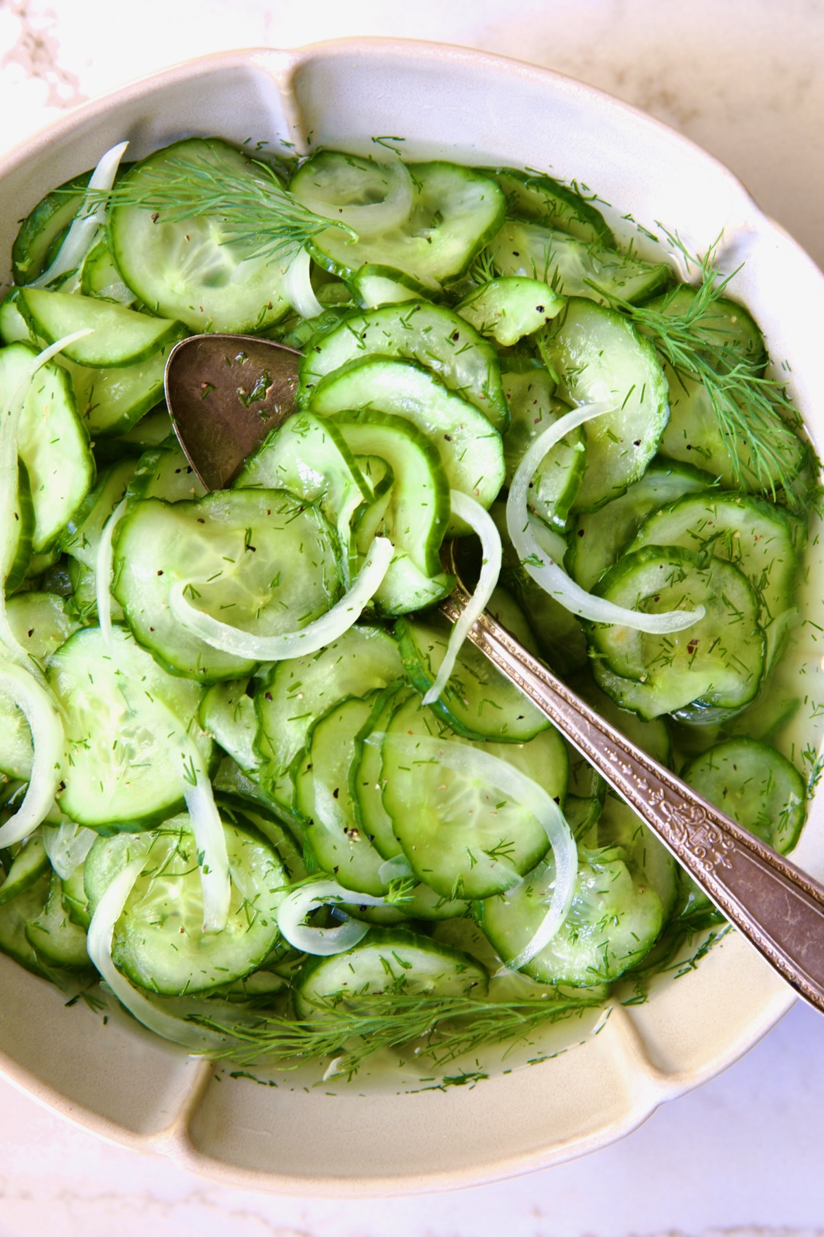 Cucumber Onion Salad in serving bowl with serving spoon.