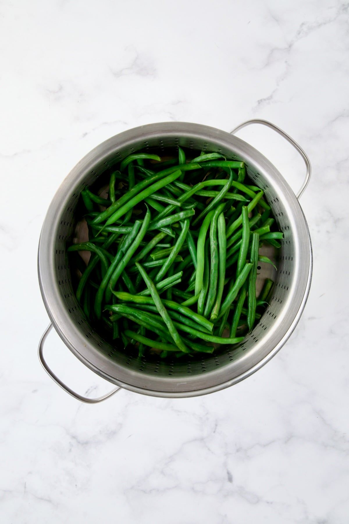 Steamed green beans in steamer rack set over pot.