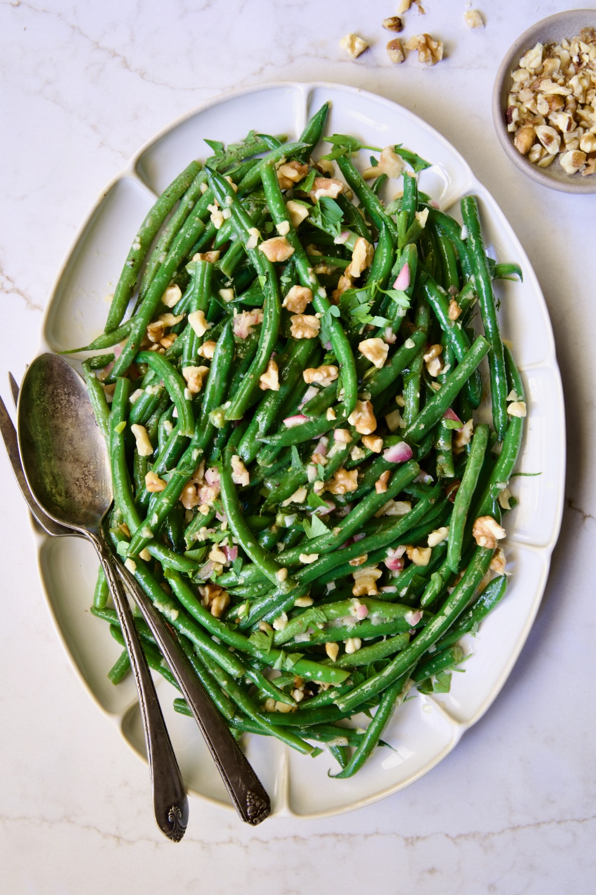 Green Bean Salad with Mustard Vinaigrette on white oval platter garnished with walnuts.