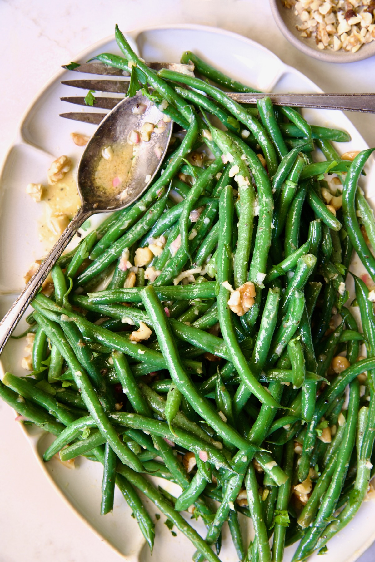 Green Bean Salad with Mustard Vinaigrette on white oval platter garnished with walnuts.