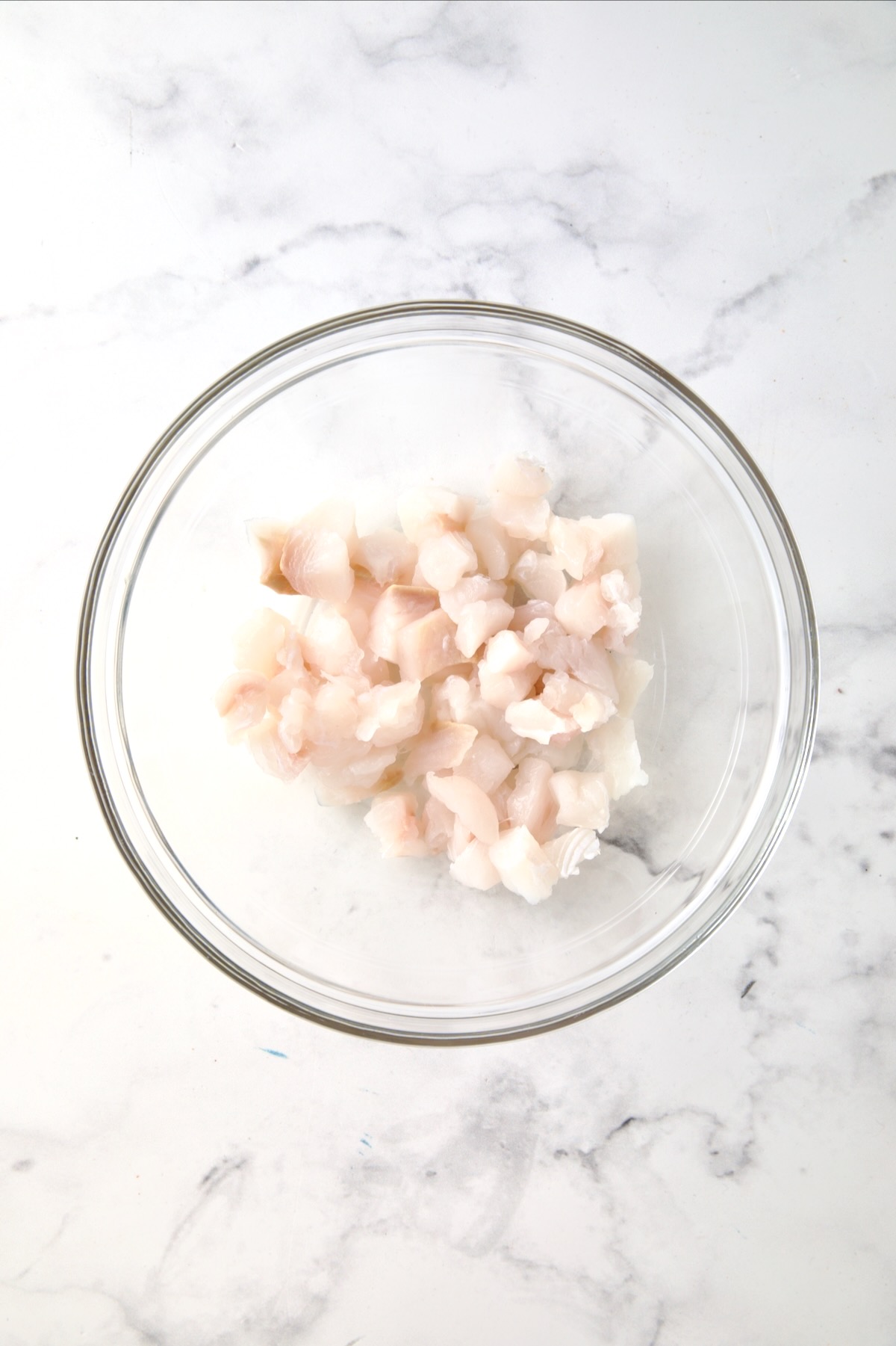 Cubes of raw halibut in glass bowl.