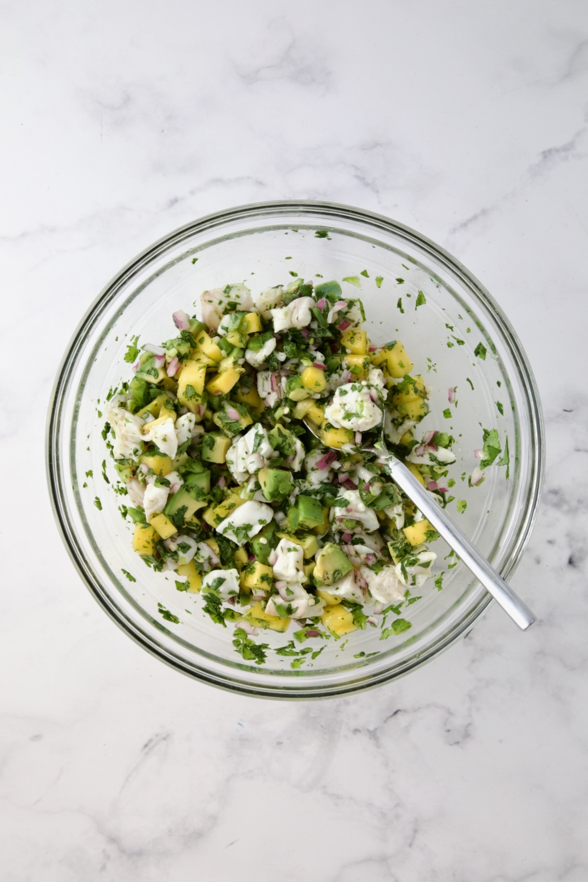 Ingredients for Halibut Ceviche combined in glass bowl.