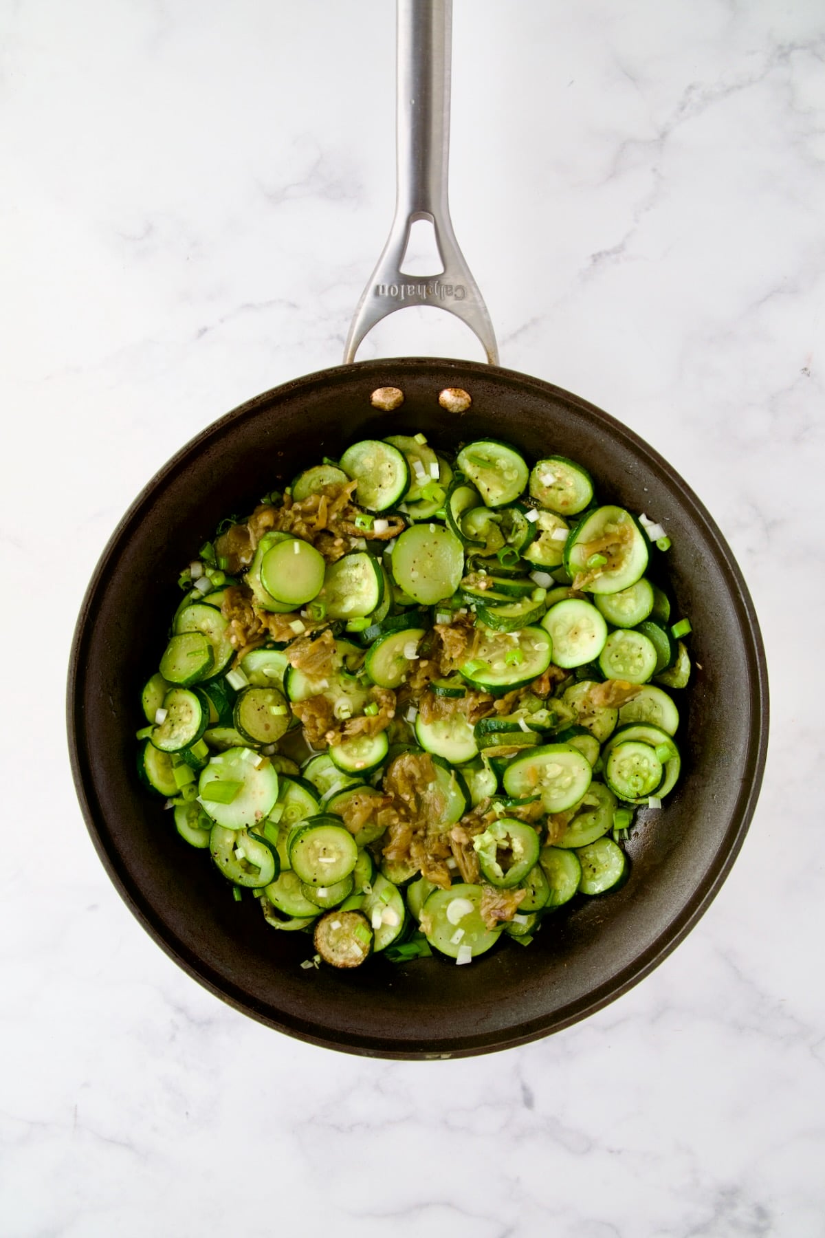 Cooked zucchini rounds, scallions and green chiles in nonstick skillet.