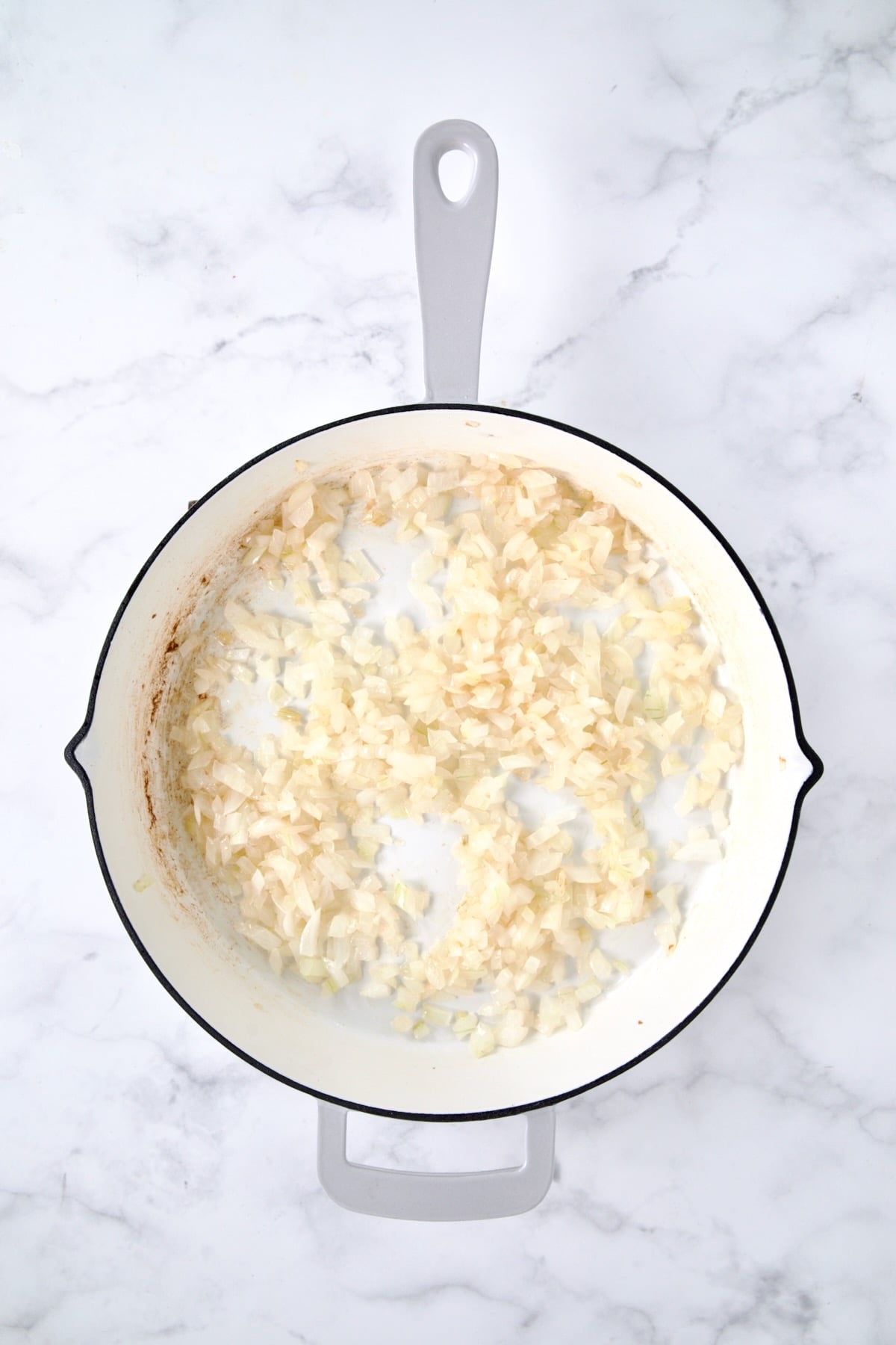 Cooked onions in white enamel cast iron skillet.