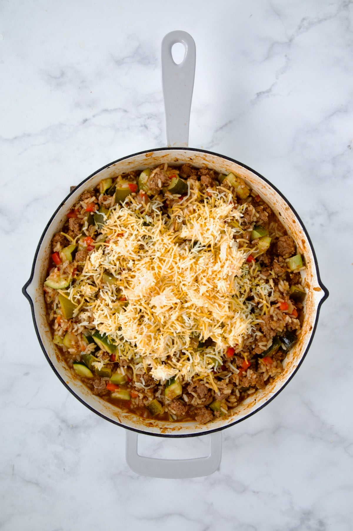 Everything cooked in white enamel cast iron skillet with cheese is added.