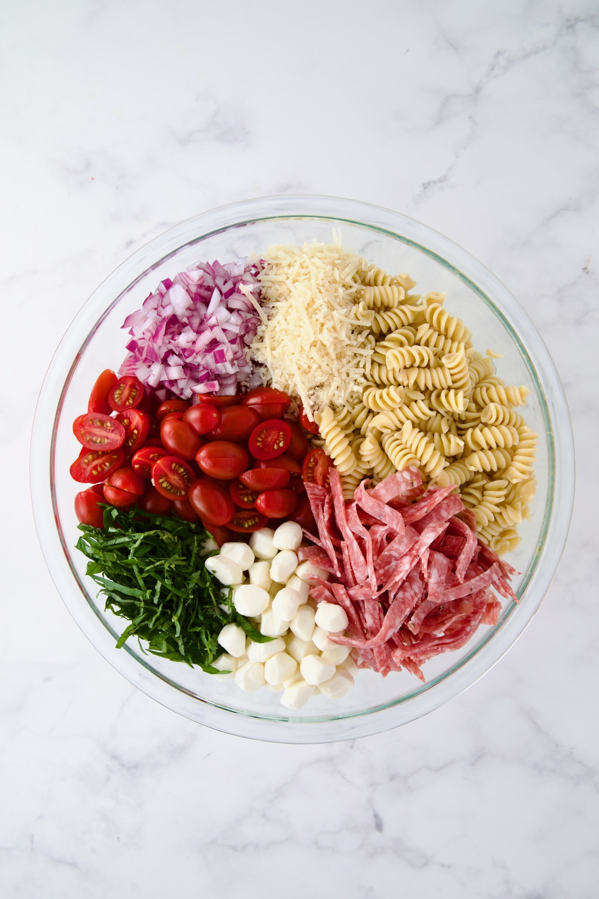 Ingredients for Caprese Pasta Salad in glass bowl before being combined.