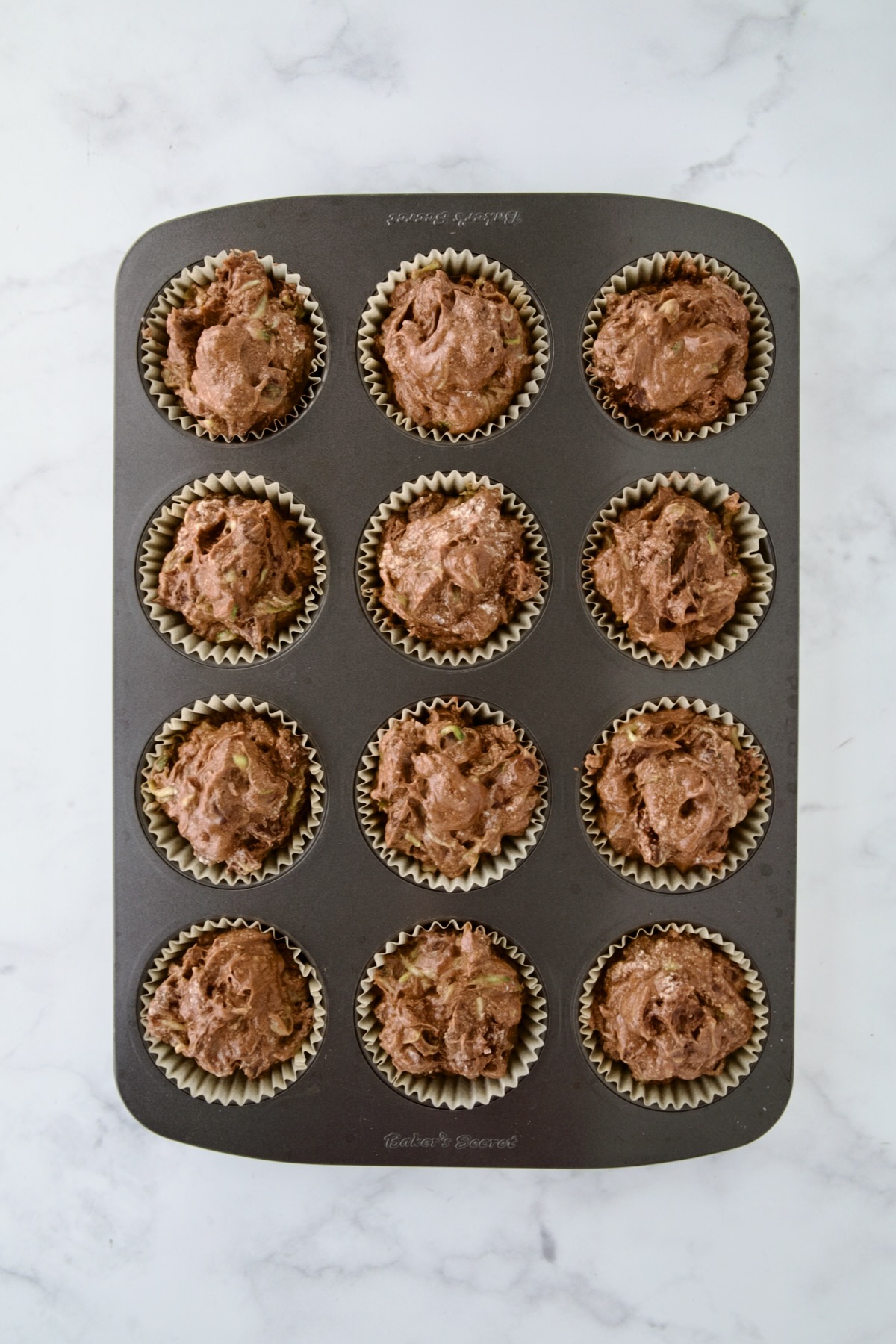 Batter for muffins in 12-cup muffin pan before being baked.