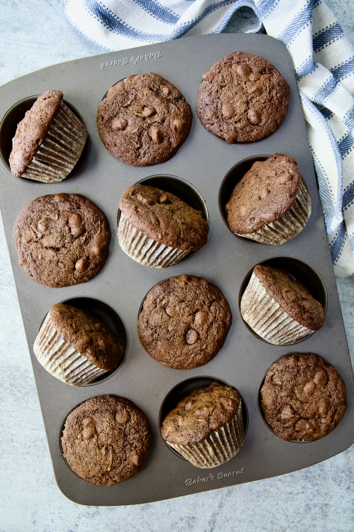 Baked Chocolate and Zucchini Muffins in 12-cup muffin pan with some turned on their sides.