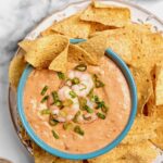 Creamy Shrimp Salsa Dip in bright blue bowl on platter with tortilla chips.