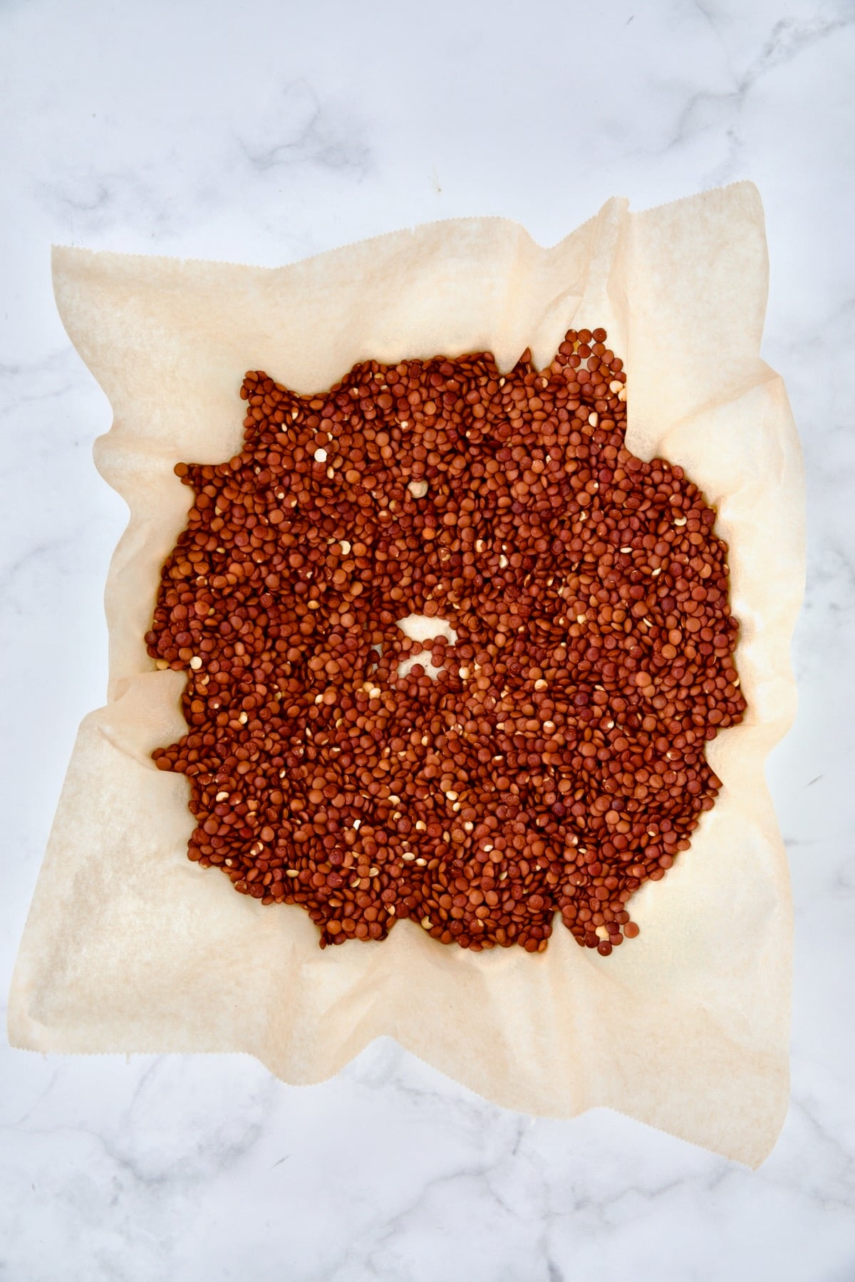 Lentils on parchment paper set over unbaked pie crust.