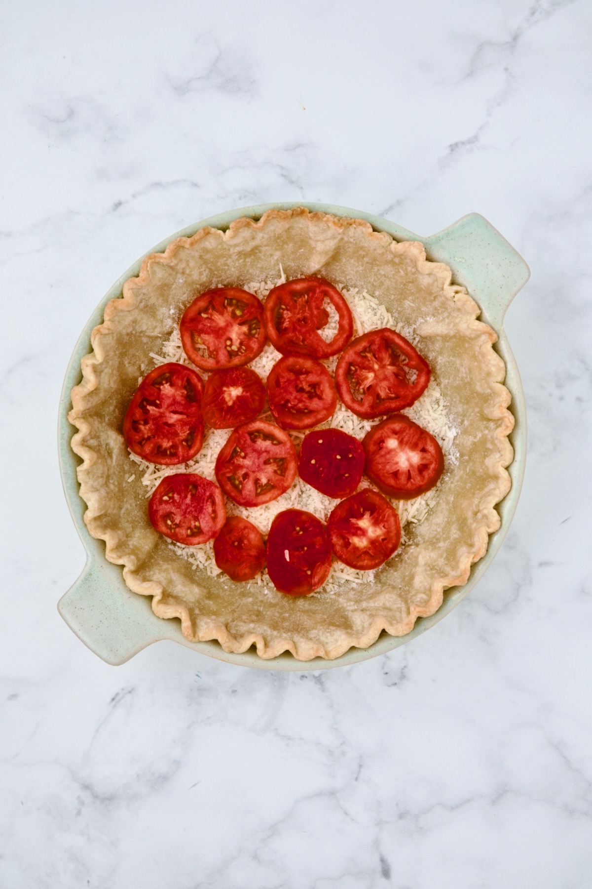 First layer of tomatoes set over Parmesan cheese and flour.