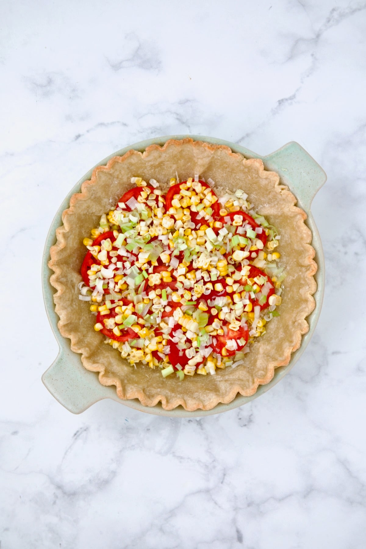 Corn and scallions sprinkled over the first layer of tomatoes in baked pie crust.