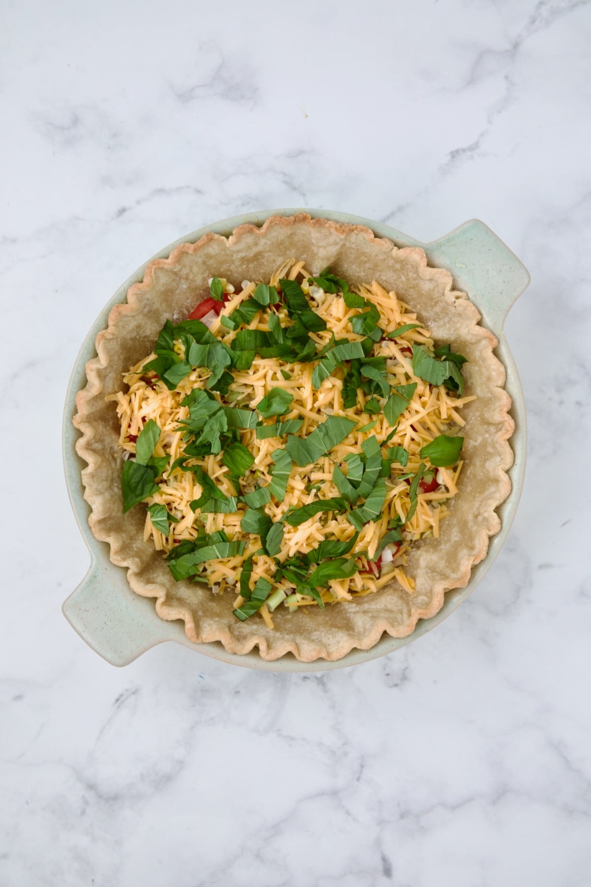 Fresh basil sprinkled over cheddar cheese.