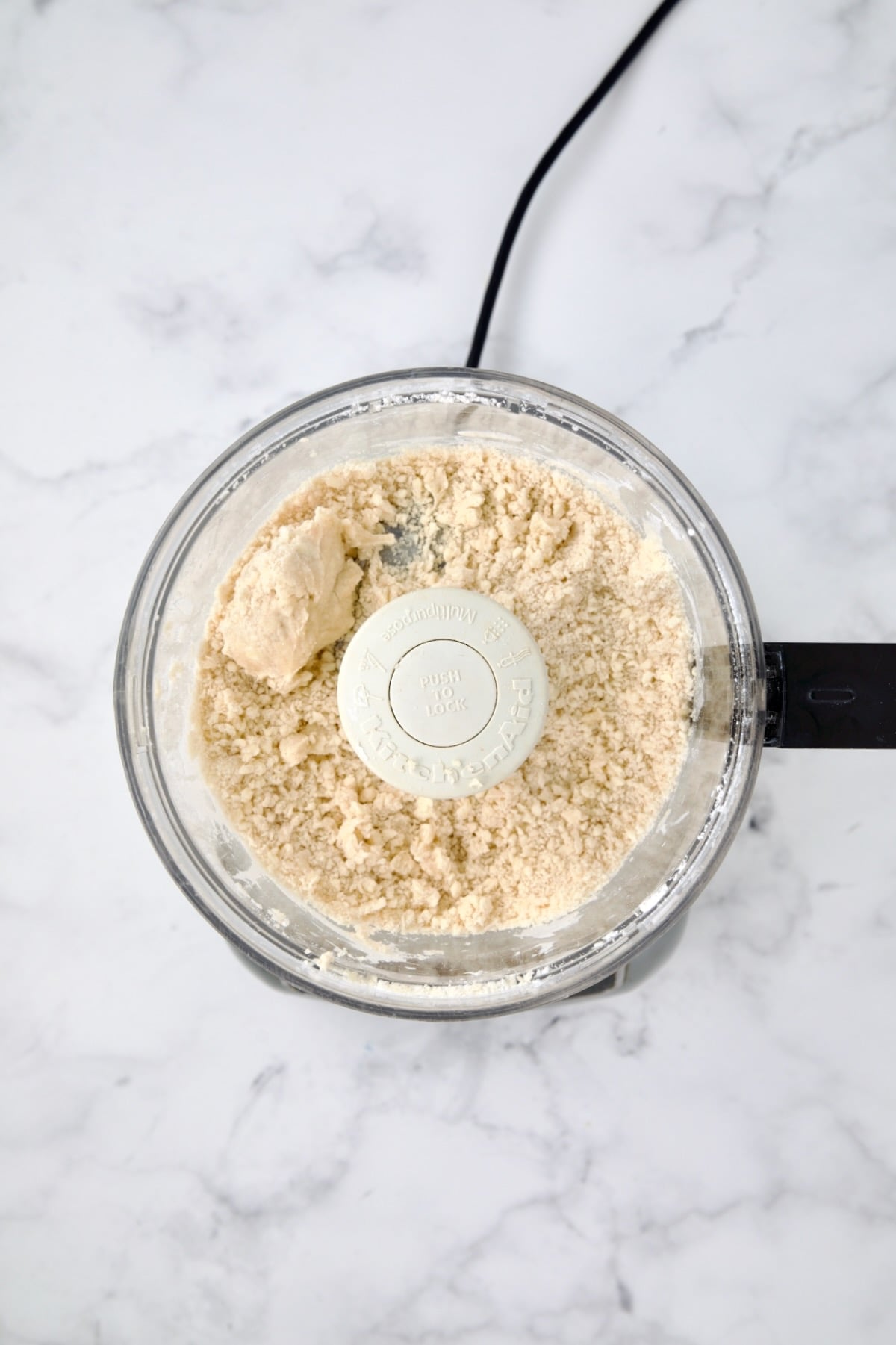 Pie crust dough in food processor bowl before being formed into a ball.