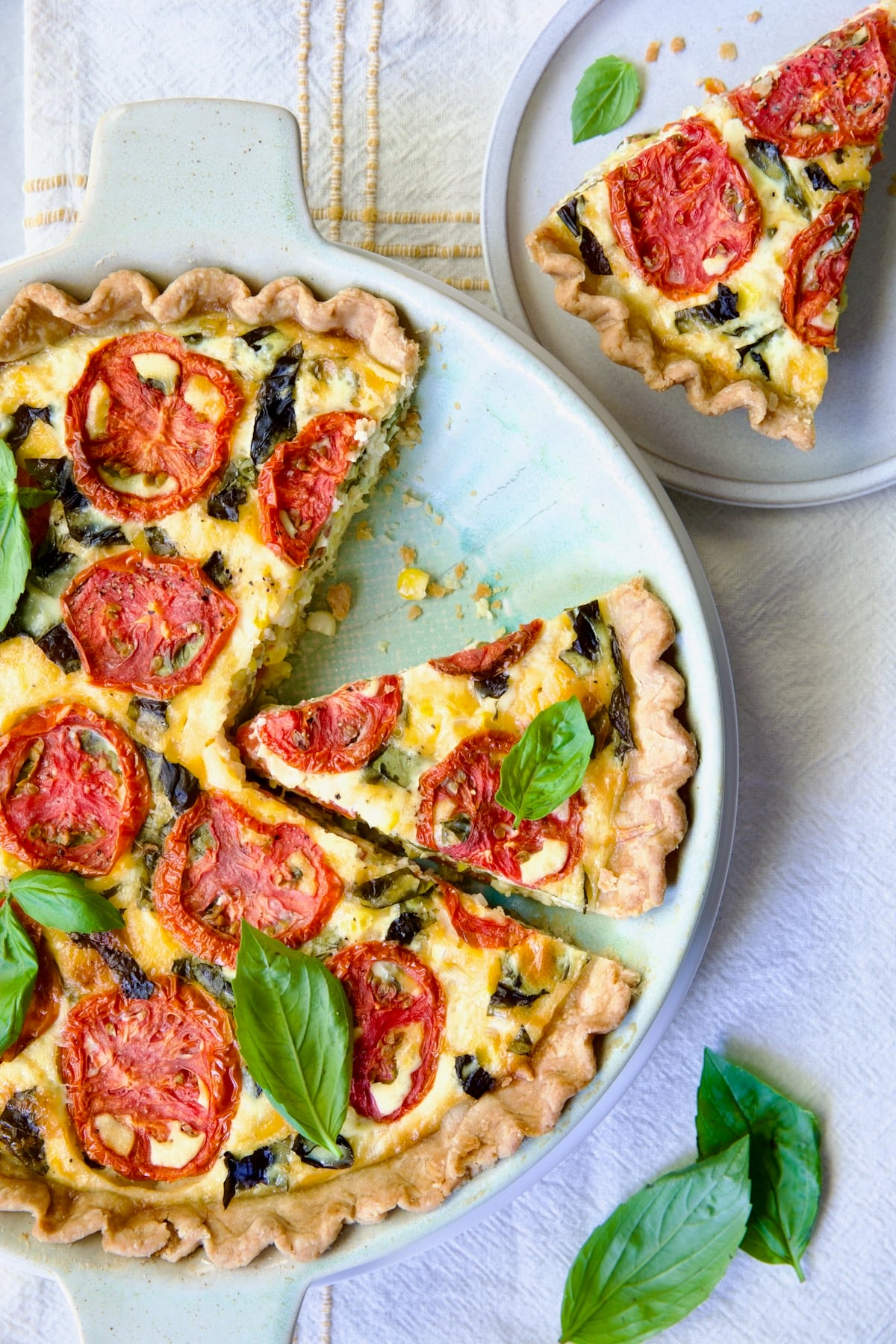 Tomato Pie Recipe with Corn and Basil with two wedges cut and one on small round white plate.