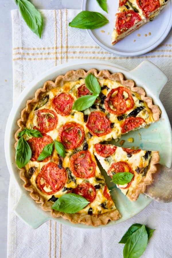 Tomato Pie Recipe with Corn and Basil on yellow striped napkin with two wedges removed garnished with fresh basil.