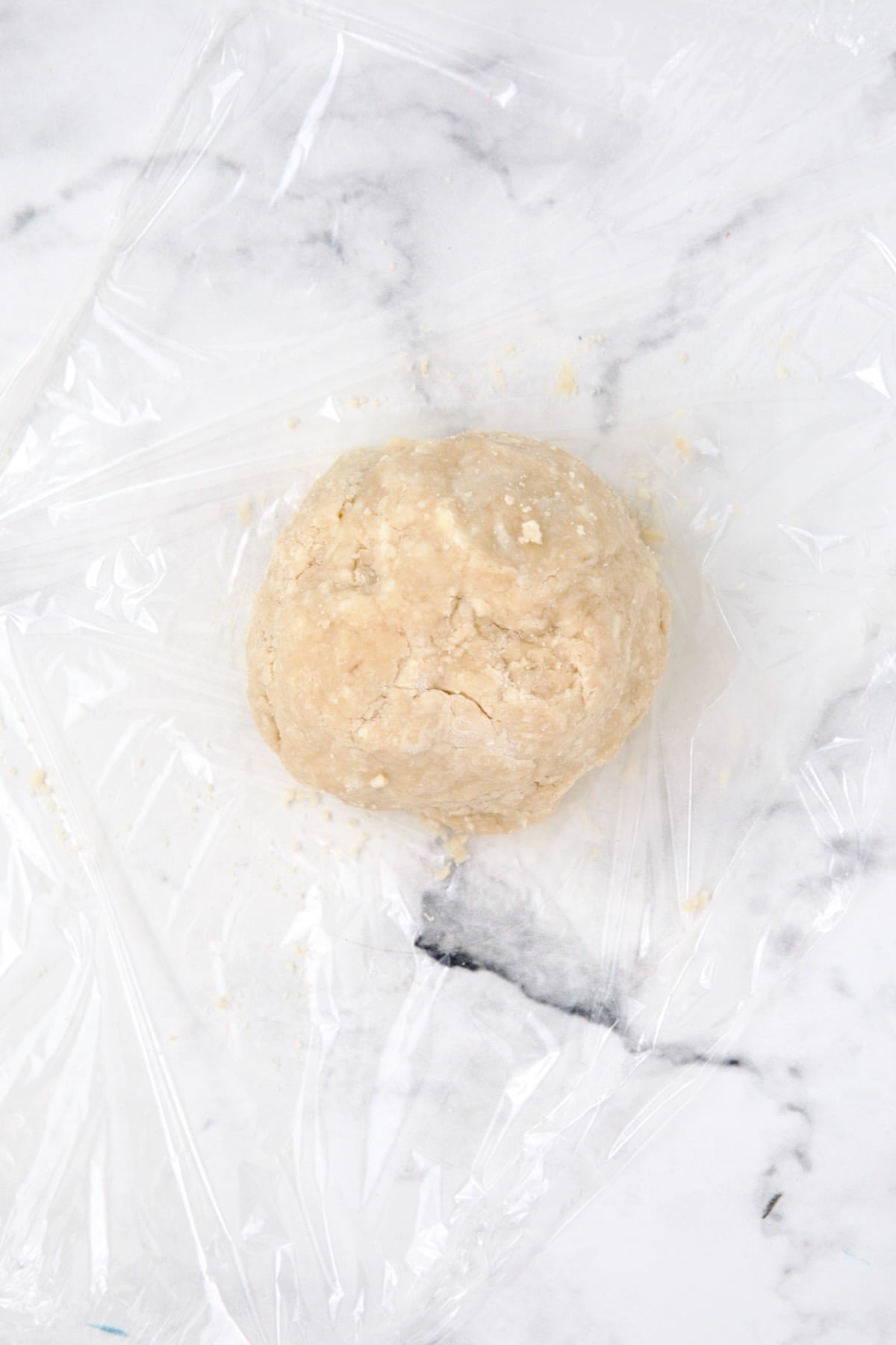 Pie crust dough ball on plastic wrap.