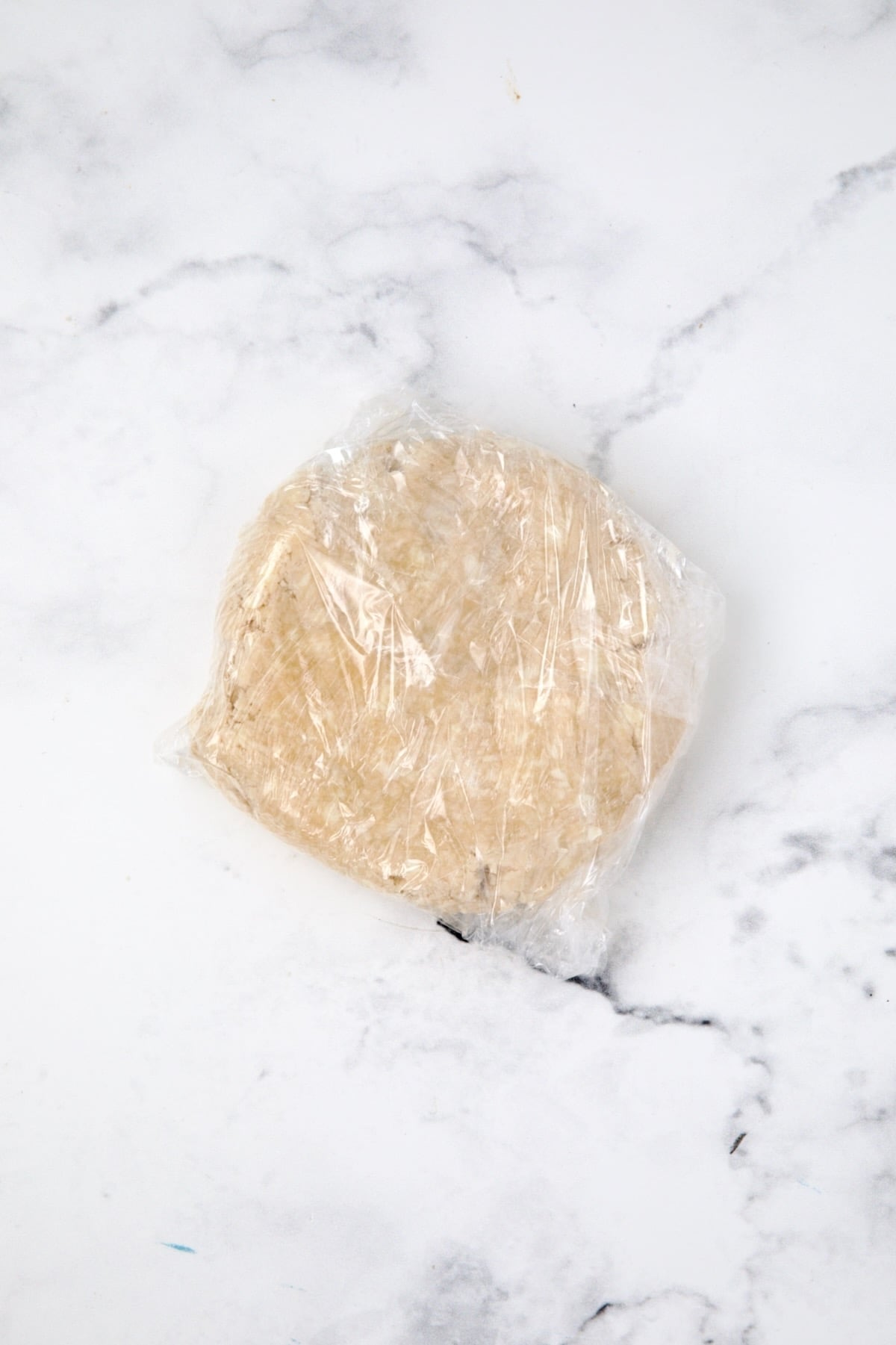 Pie crust dough wrapped in plastic wrap.