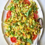 Grilled Corn Succotash on white oval platter garnished with fresh basil leaves.