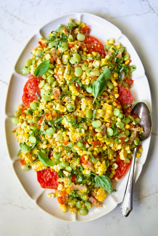 Grilled Corn Succotash on white oval platter garnished with fresh basil leaves.