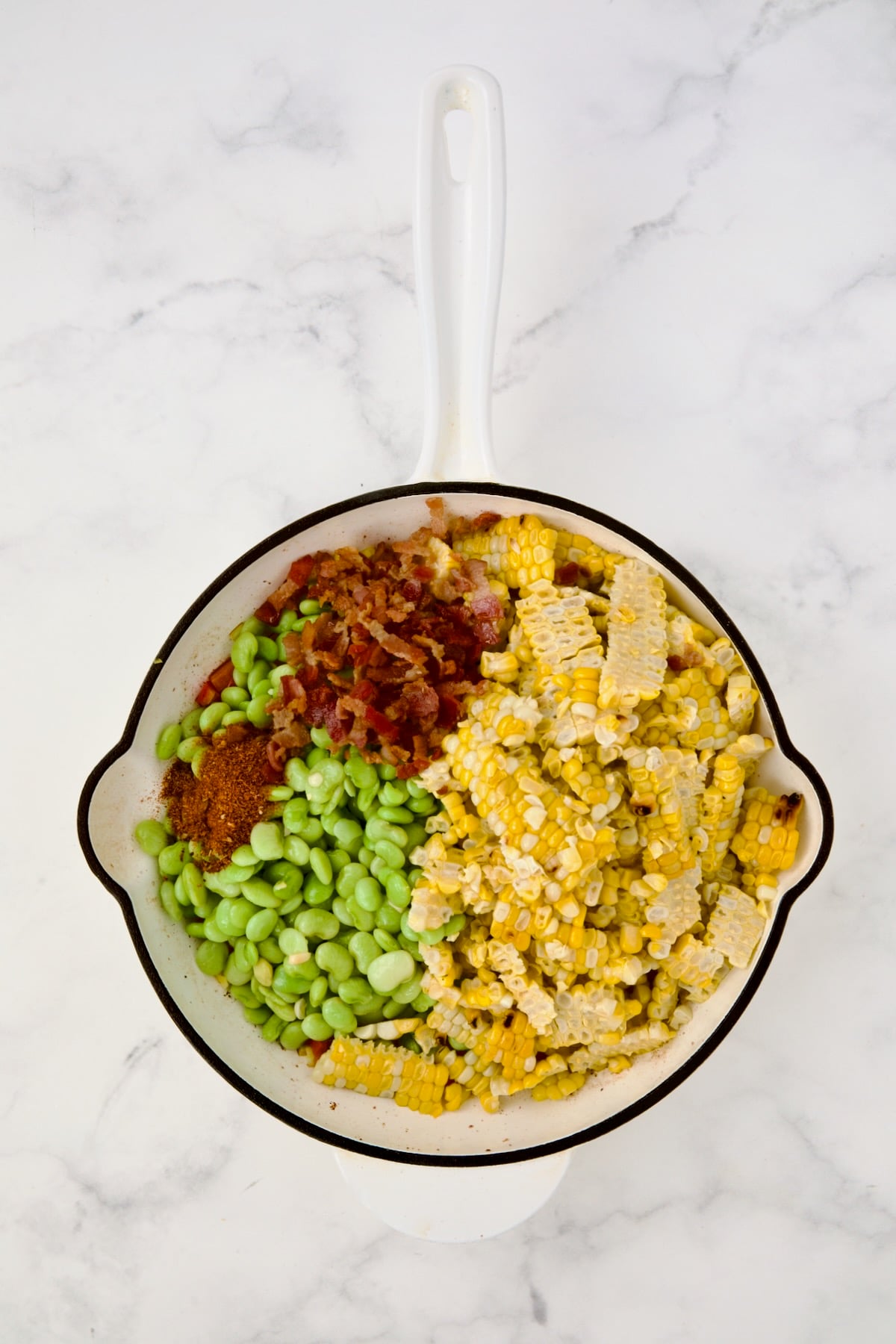 Corn, lima beans and bacon added to red bell pepper and scallion in white enamel cast iron skillet.