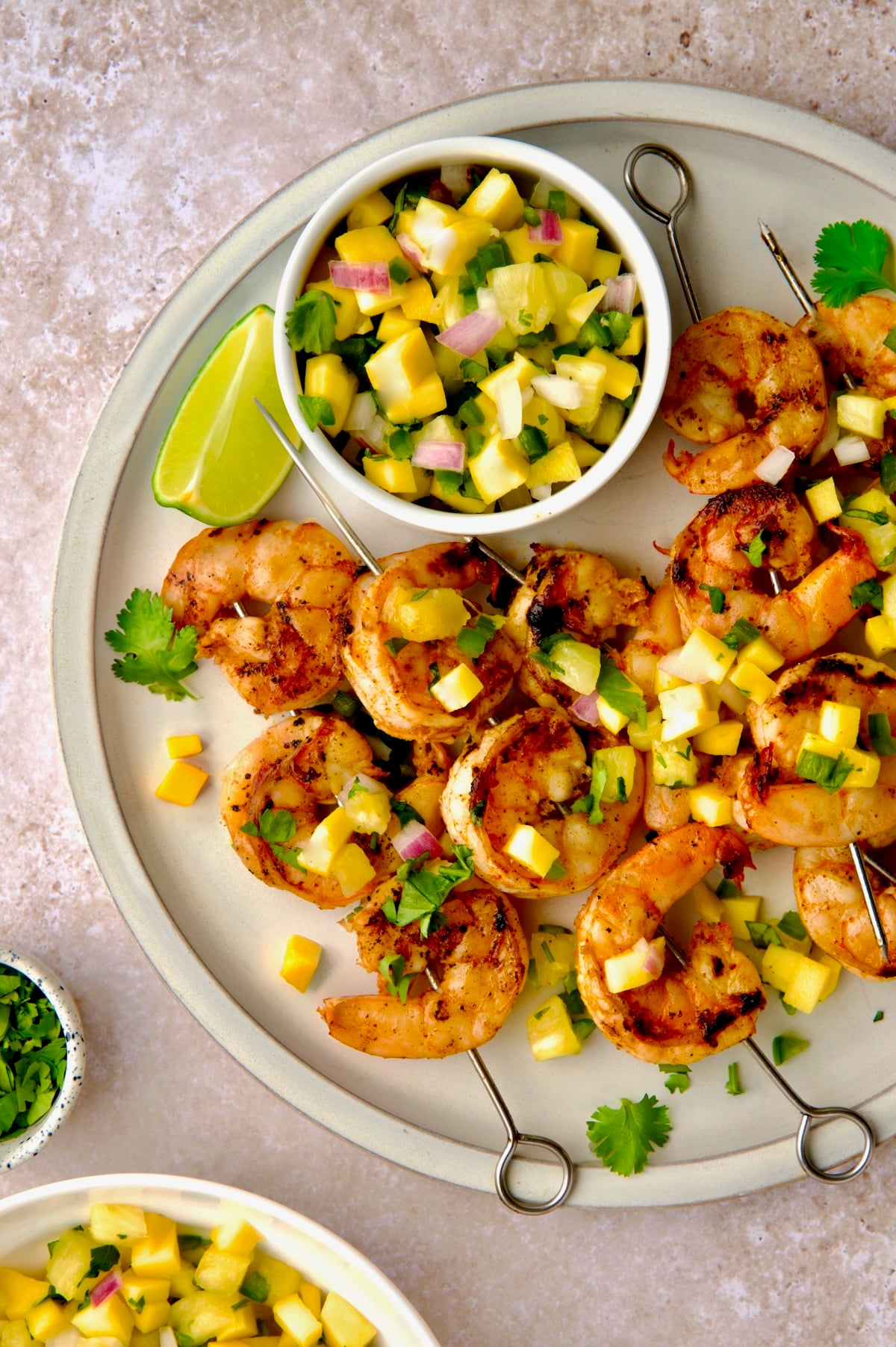 Grilled Shrimp Skewers with Mango Pineapple Salsa on round white plate.