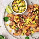 Grilled Shrimp Skewers with Mango Pineapple Salsa on round white plate.