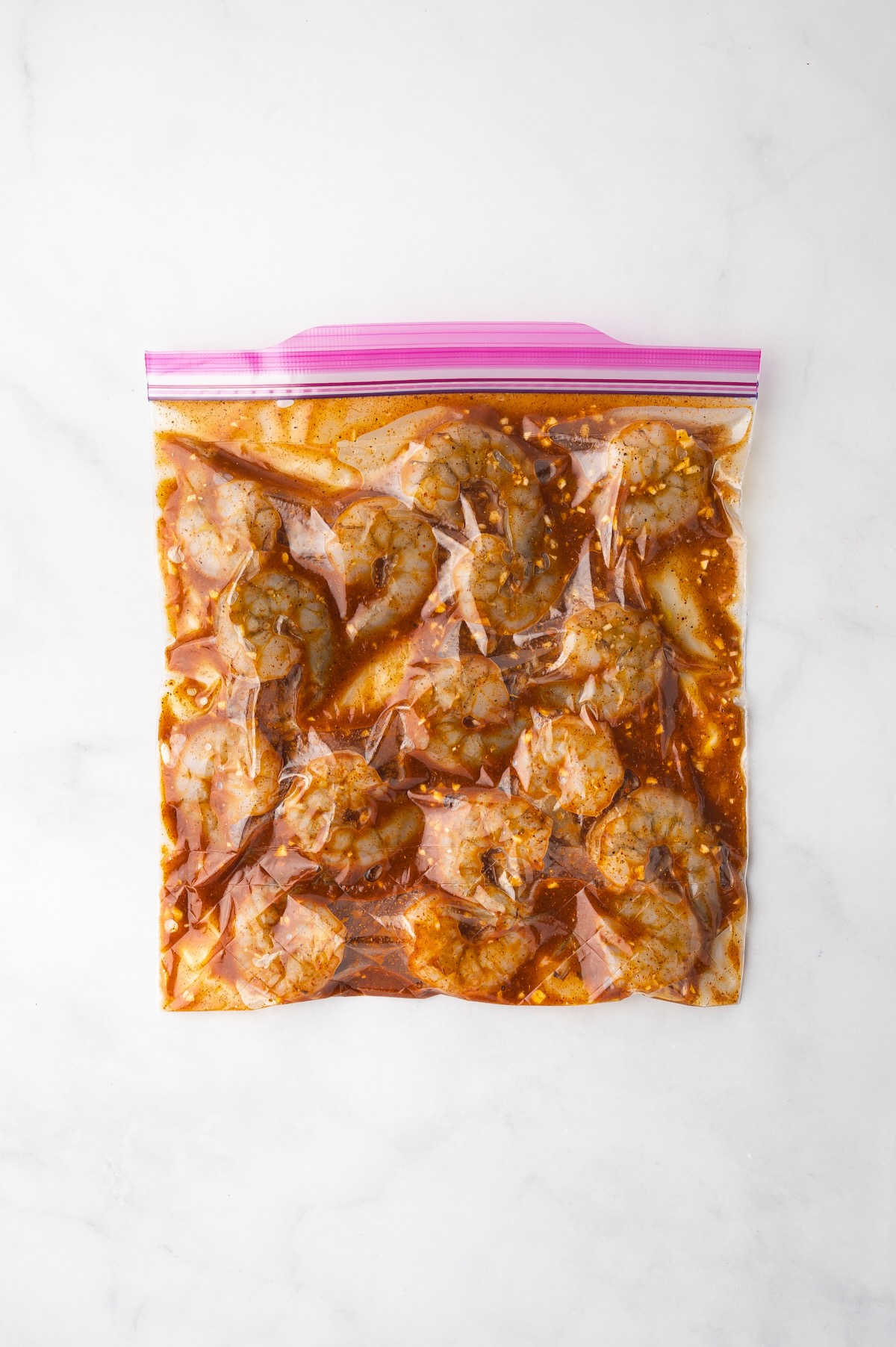 Shrimp in marinade in zipper top bag.