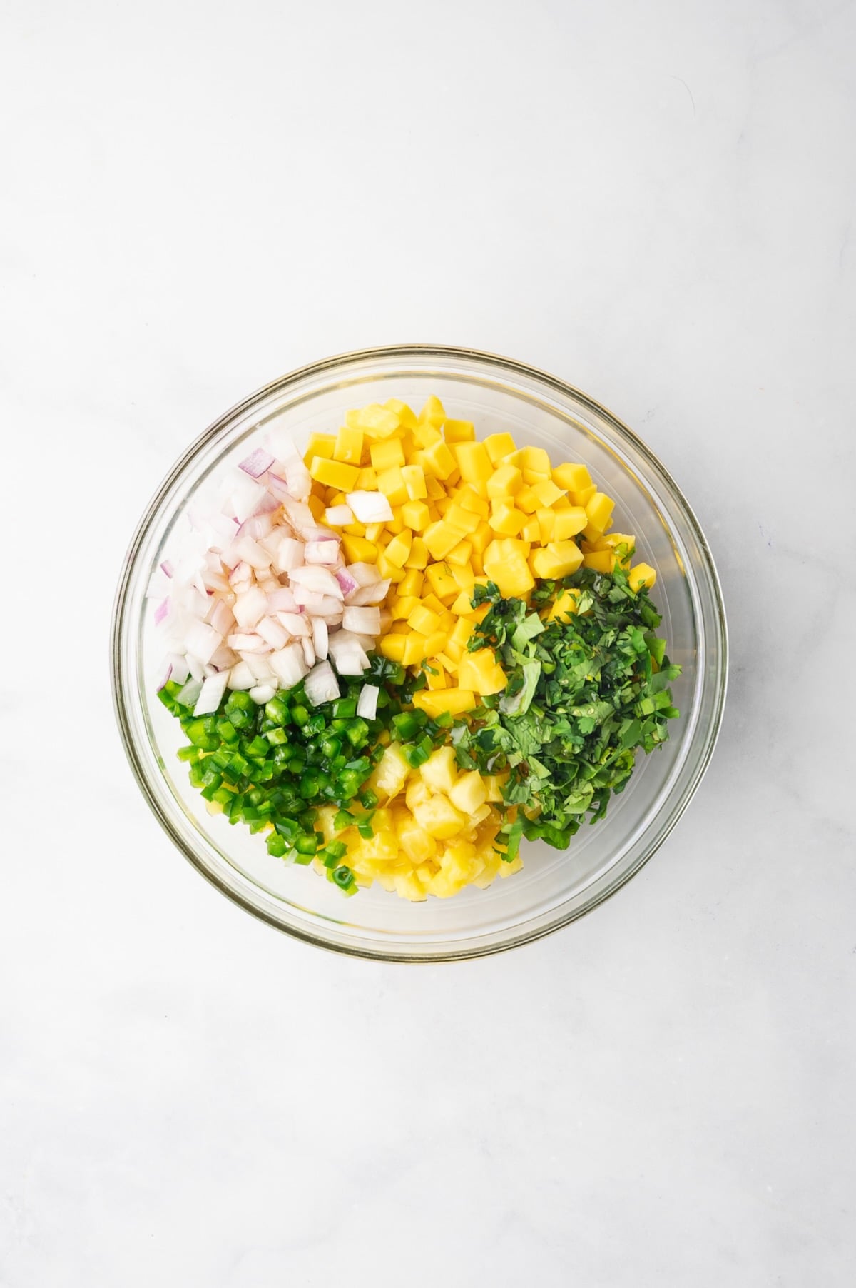 Ingredients for Pineapple Mango Salsa in glass bowl before being mixed together.