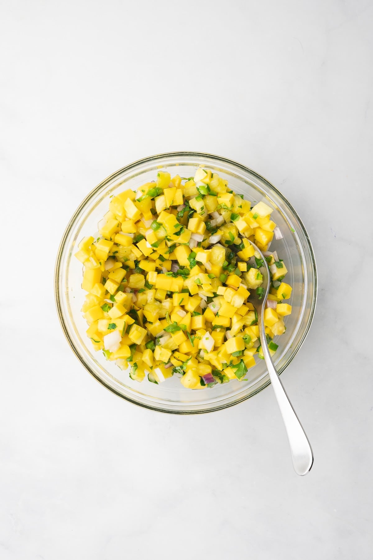 Ingredients for Pineapple Mango Salsa in glass bowl after being mixed together.