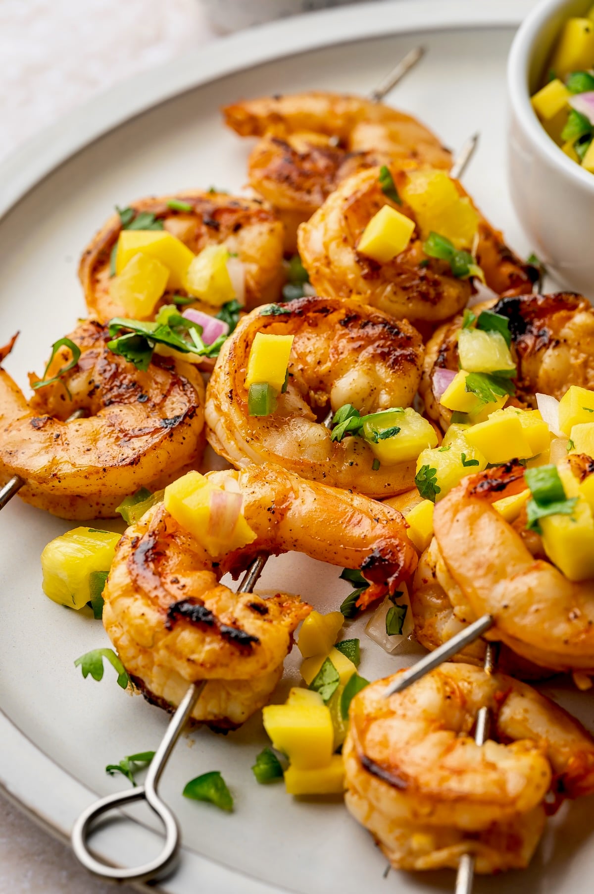 Grilled Shrimp Skewers with Mango Pineapple Salsa on round white plate.
