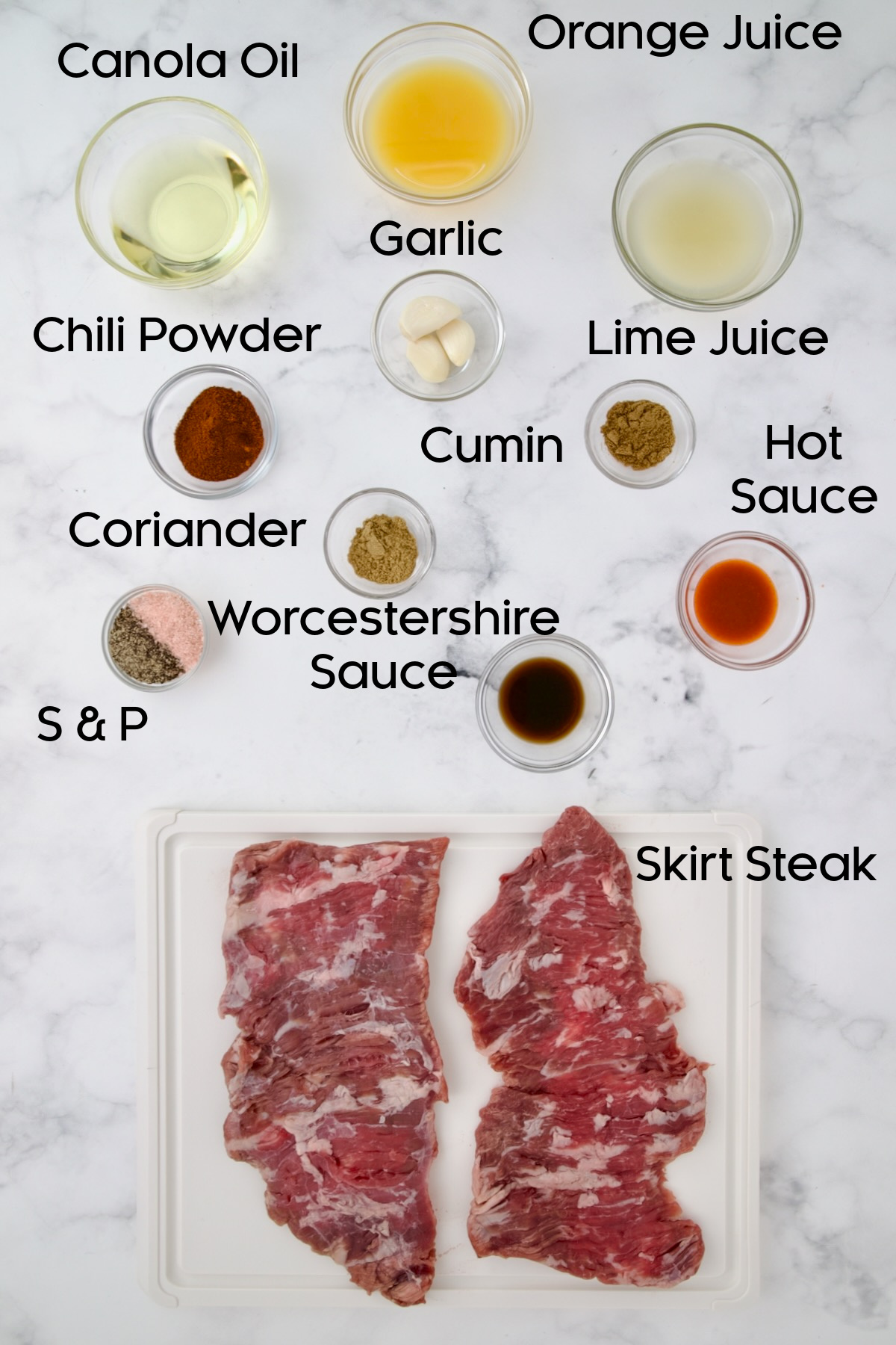 Ingredients for Grilled Skirt Steak in glass bowls with skirt steak on a white plastic cutting board.