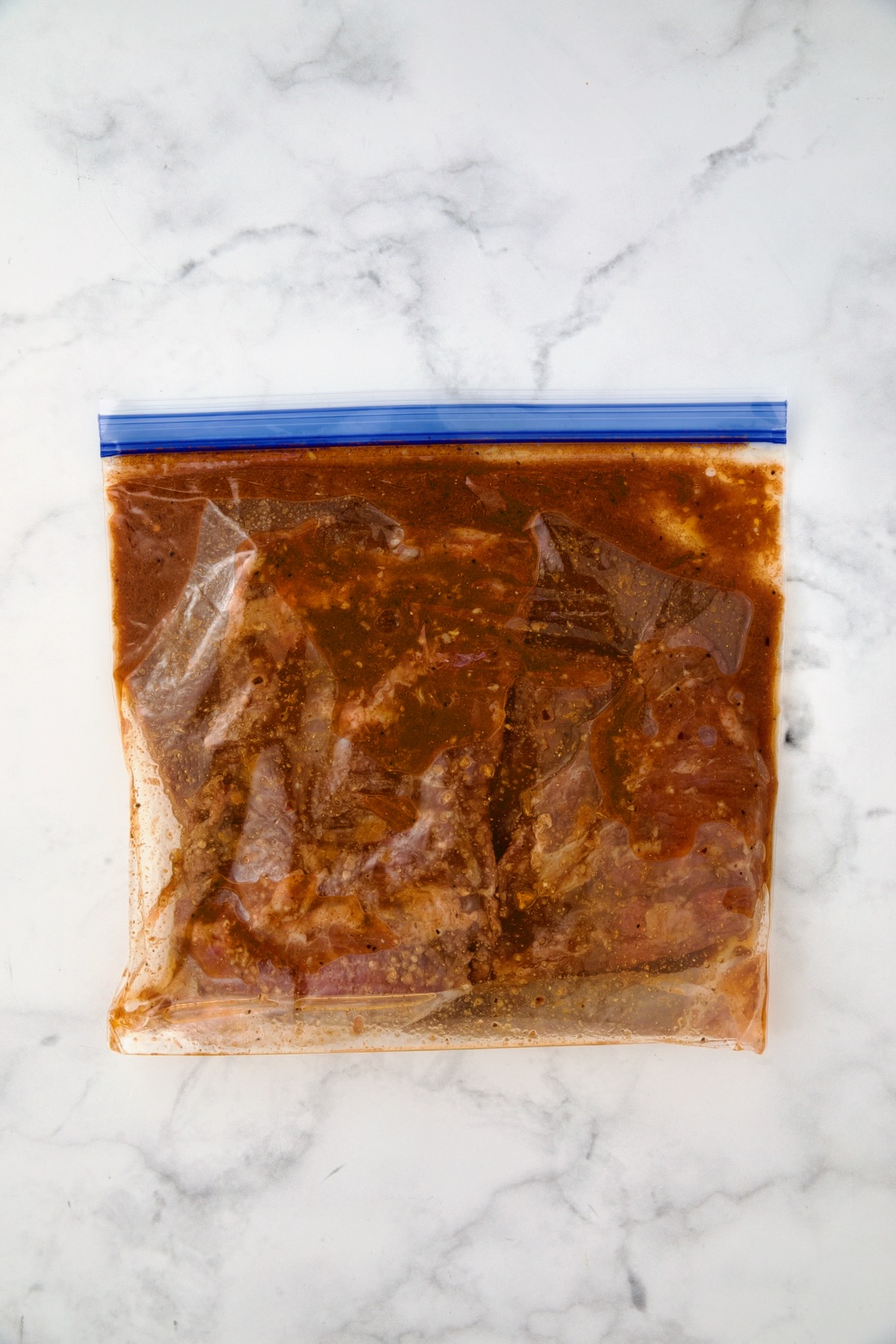 Skirt steak in marinade in gallon-size zipper-top bag.