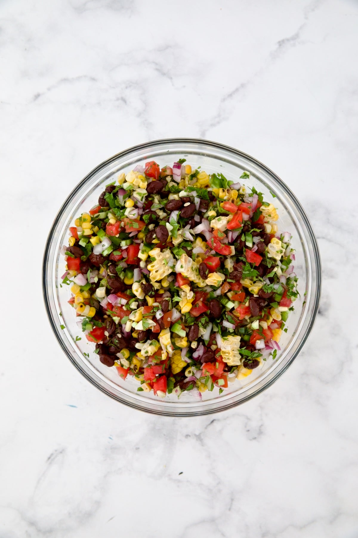 Ingredients for Black Bean Corn Tomato Salad in glass bowl after being combined.