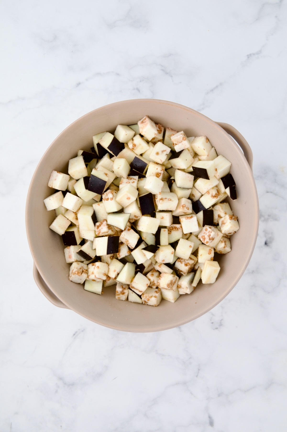 Cubes of eggplant in beige colander.