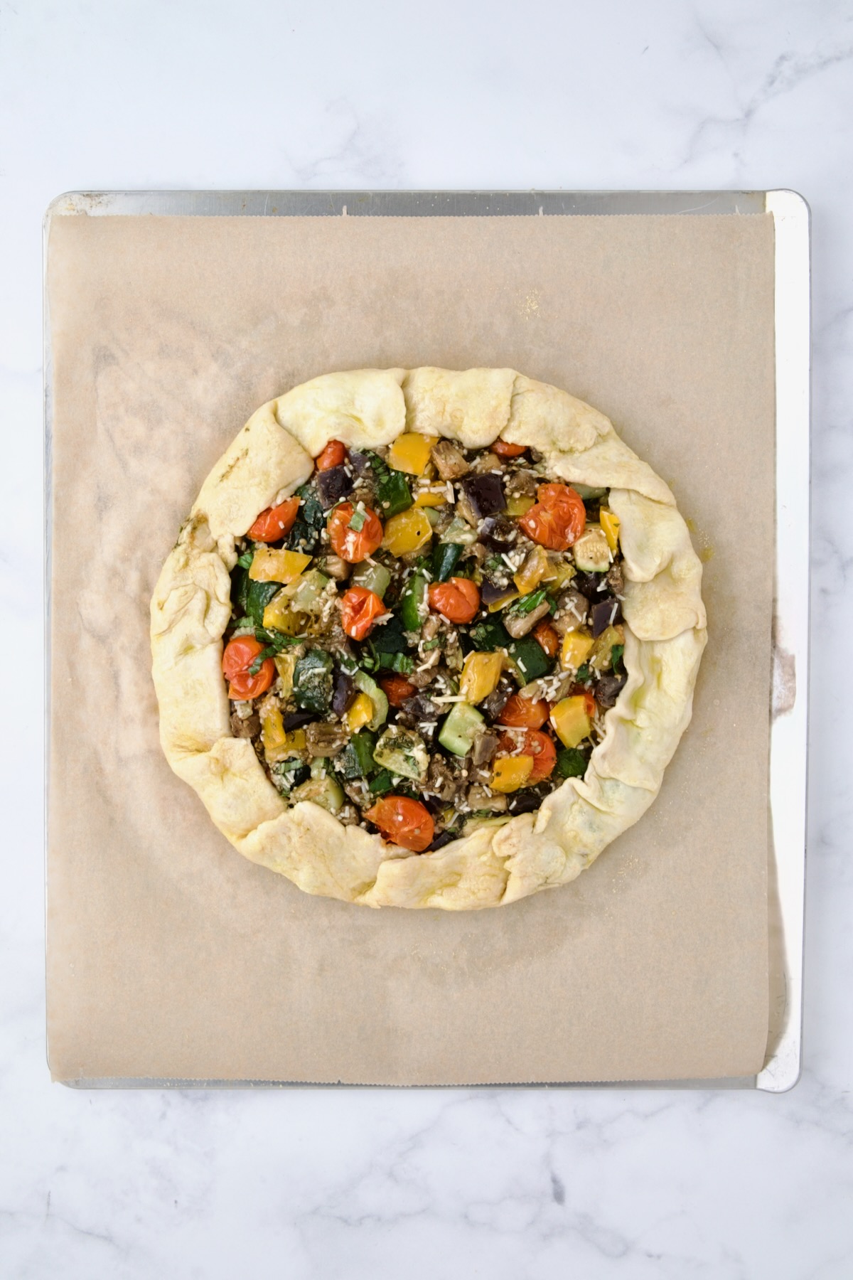 Fully assembled galette on parchment paper on cookie sheet before being baked.