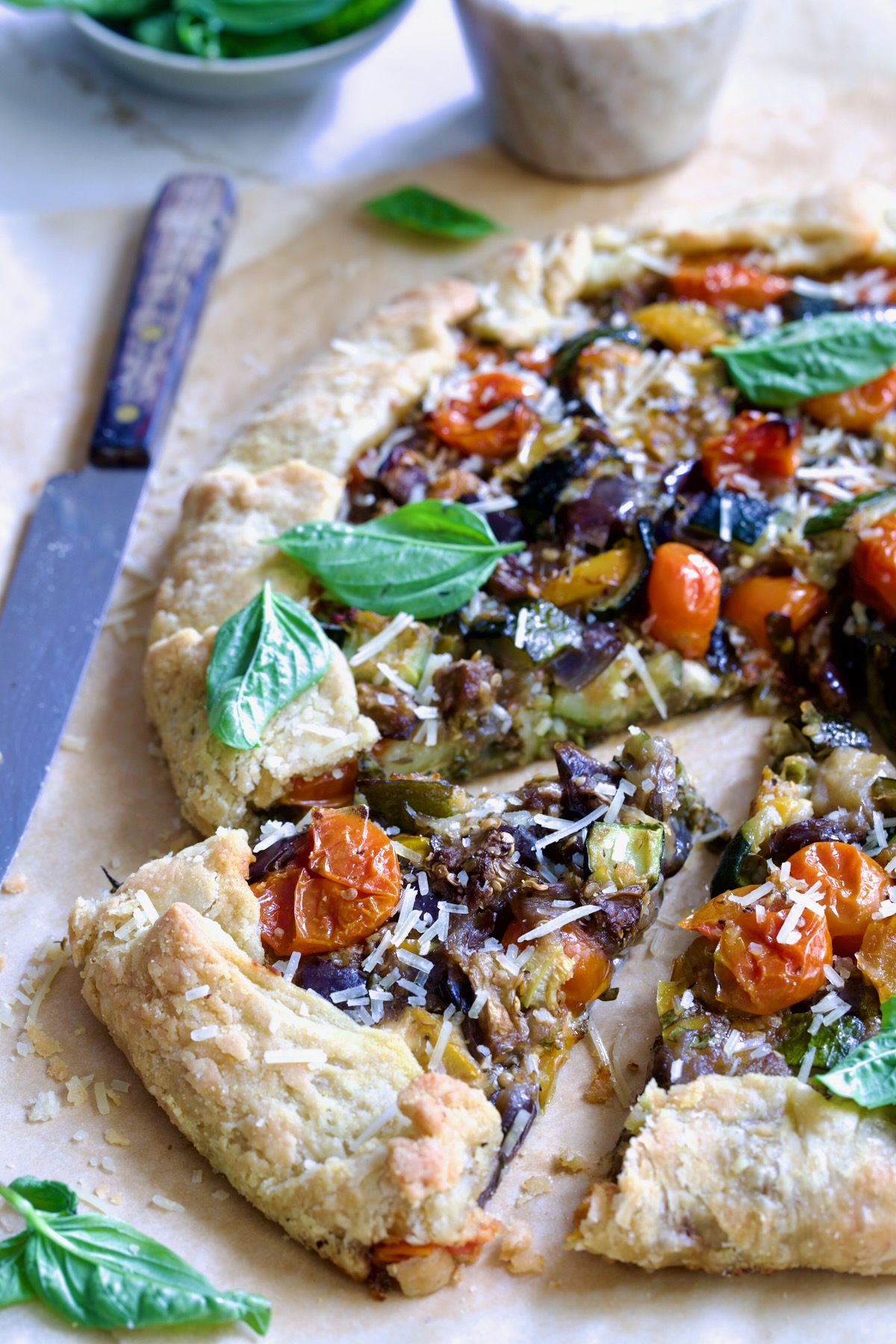 Cut wedges of Mediterranean Vegetable Galette on parchment paper.